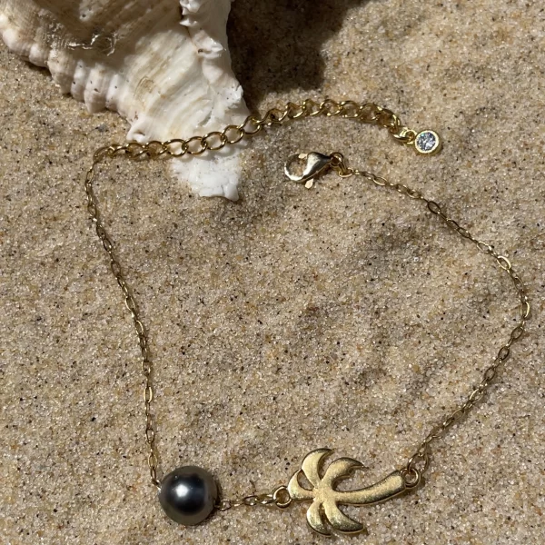 Bracelet perle de Tahiti avec cocotier dorée sur sable fin