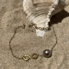 Bracelet infinity doré sur sable avec coquillage