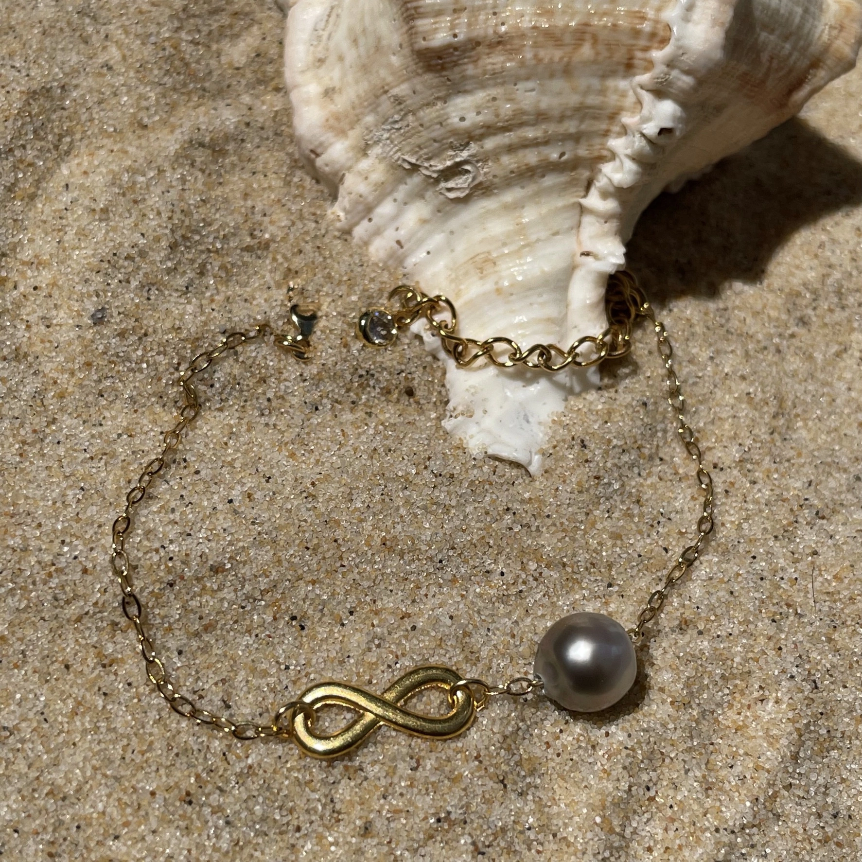 Bracelet infinity doré sur sable avec coquillage Bracelet infinity doré sur sable avec coquillage