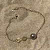 Bracelet infinity doré sur sable fin