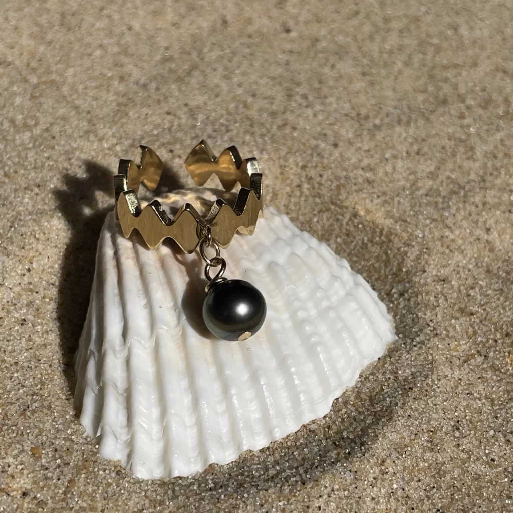 Bague dorée en acier inoxydable fait main avec perle de Tahiti de forme losange, étincelant sur le sable