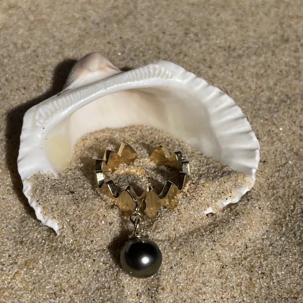 Bague unique en acier inoxydable doré avec perle de Tahiti de forme losange, brillant sous le soleil sur le sable