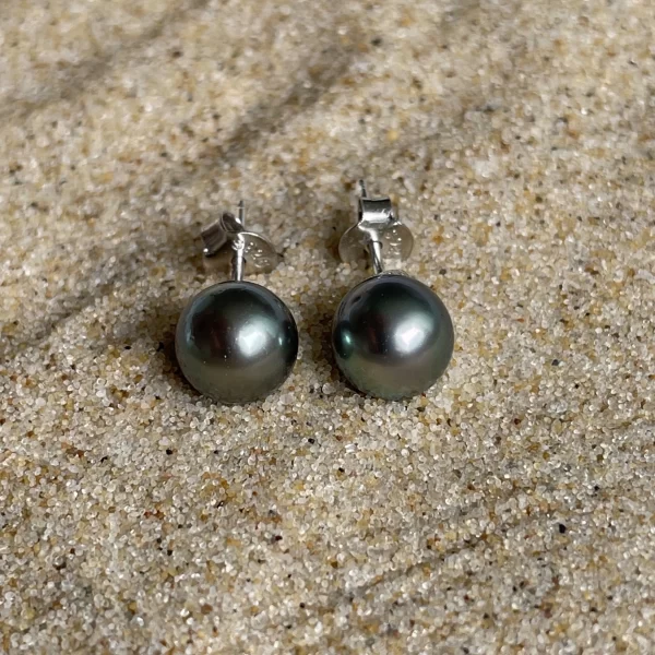 Vue rapprochée de boucles d'oreilles artisanales en acier argenté mettant en valeur les perles de Tahiti